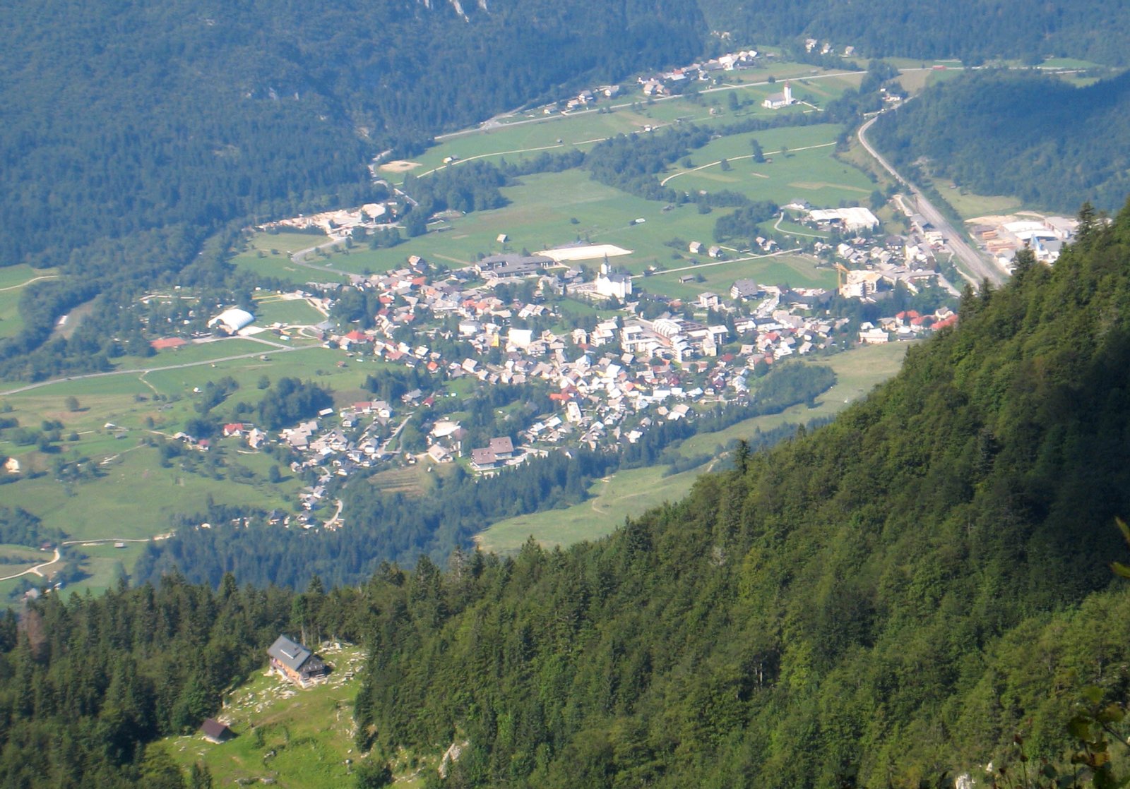 Bohinjska Bistrica from above (near Črna prst, to the south). The mountain hut you can see in the foreground (somewhat) is the new "Orožnova koča" in the Za Liscem alpine pasture at 1346 m altitude. The original Orožnova koča was the first mountain hut in Slovenia, but later burnt down. | Bohinjska Bistrica in Slovenia
