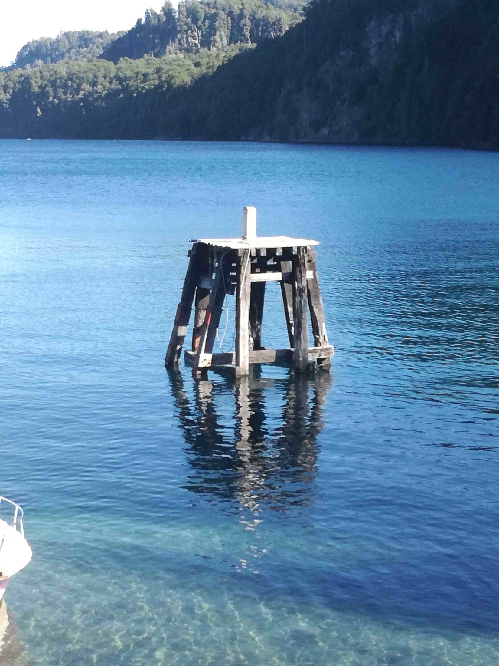 Situado en el muelle de Bahia Mansa sobre el lago Nahuel Huapi en la localidad de Villa La Angostura, una pequeña infraestructura de madera donde anclan las embarcaciones. Esta infraestructura fue popularmente conocida durante el año 2013, cuando el interprete Indio Solari presento su disco "Pajaritos, Bravos Muchachitos" en el cual se observa este paisaje junto un ángel desde la orilla. | Villa La Angostura in Argentina